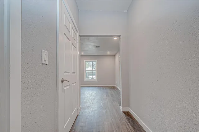 a view of a hallway with wooden floor and a window