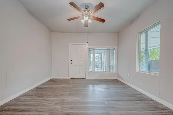 a view of an empty room with window and wooden floor