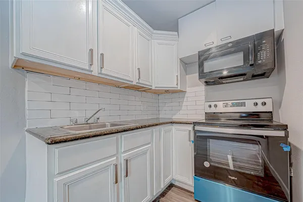 a kitchen with stainless steel appliances granite countertop white cabinets and a stove top oven