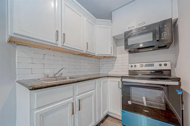 a kitchen with stainless steel appliances granite countertop white cabinets and a stove top oven