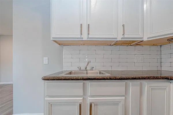 a kitchen with granite countertop white cabinets and a white stove