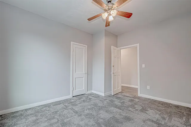 an empty room with closet and a chandelier fan
