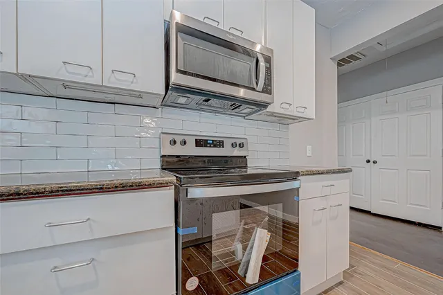 a kitchen with stainless steel appliances white cabinets and a wooden floor