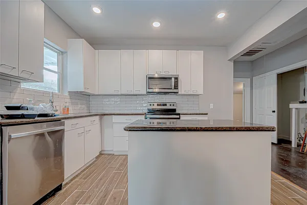 a kitchen with granite countertop a refrigerator stove top oven and sink