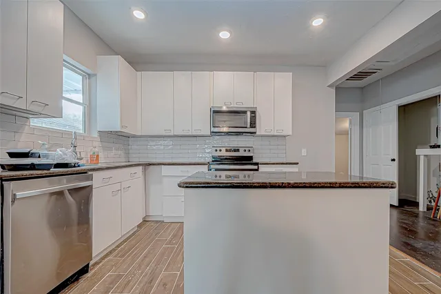 a kitchen with granite countertop a refrigerator stove top oven and sink