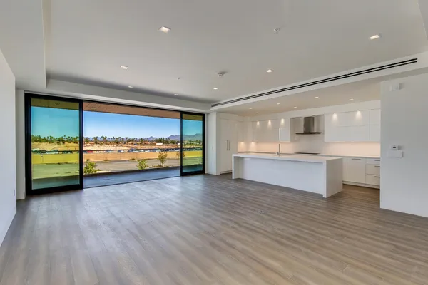 a view of an empty room with a window and wooden kitchen