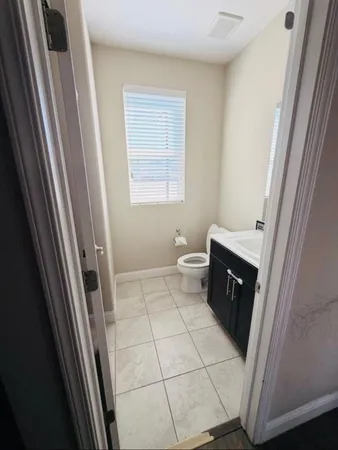 a bathroom with a sink a toilet a window and vanity