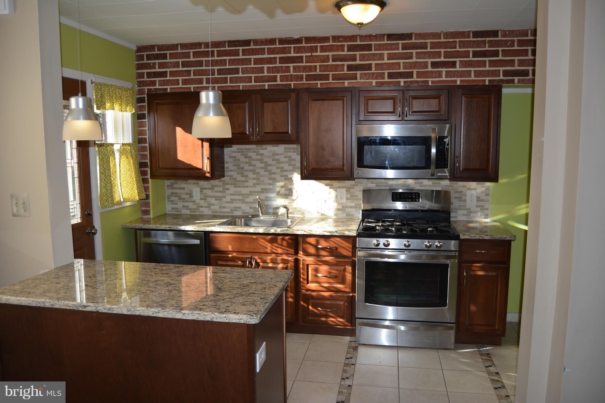 8004 Charlesmont Road Baltimore, MD 21222 - Photo 3 of 18 a kitchen with stainless steel appliances granite countertop a stove a sink and a microwave