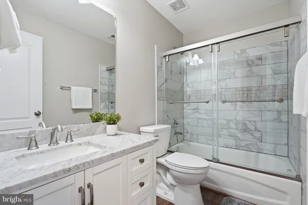 a bathroom with a granite countertop sink a toilet and shower