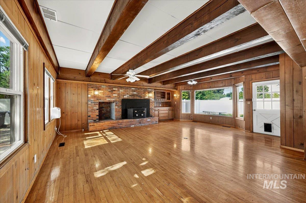 2160 South Five Mile Road Boise, ID 83709 - Photo 15 of 41 Spacious room featuring wood-finish flooring, wood paneling, and an exposed beam ceiling