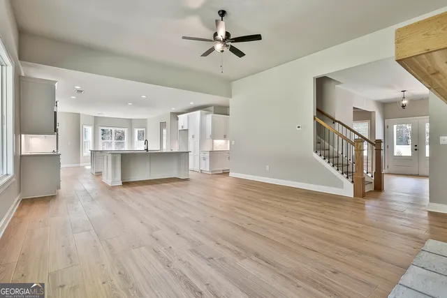 a view of a living room kitchen with a kitchen a ceiling fan wooden floor and a kitchen