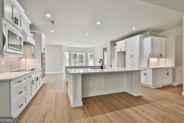 a kitchen with white cabinets and wooden floors