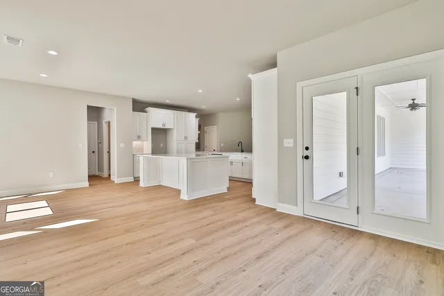 a large white kitchen with a refrigerator a sink dishwasher and white cabinets with wooden floor