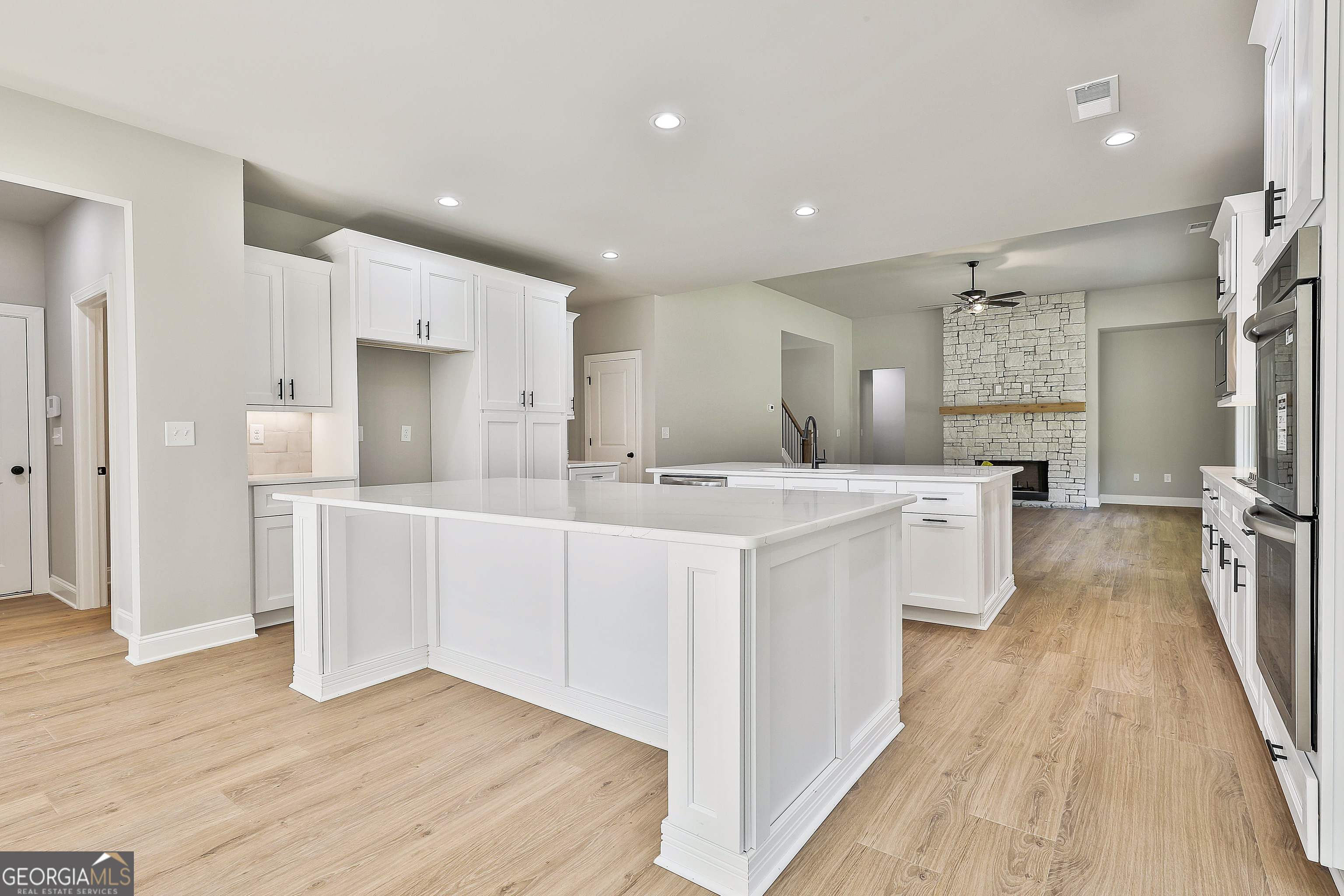 779 Alex Stephens Road Moreland, GA 30259 - Photo 28 of 54 a large white kitchen with a refrigerator a sink dishwasher and white cabinets with wooden floor