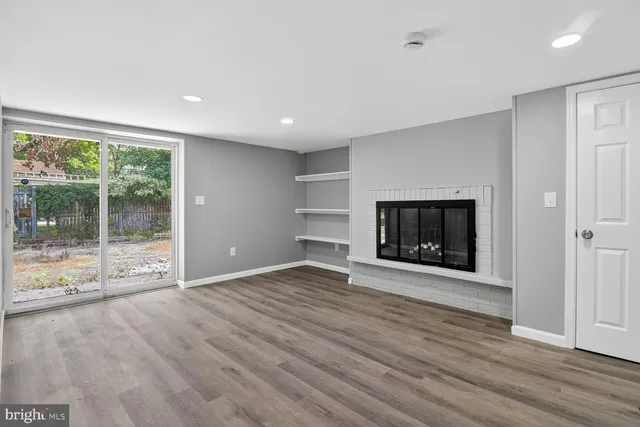 a view of empty room with wooden floor and fireplace