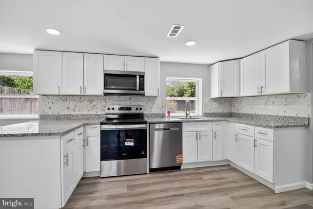 a kitchen with stainless steel appliances granite countertop a stove top oven a sink dishwasher and a microwave oven with cabinets