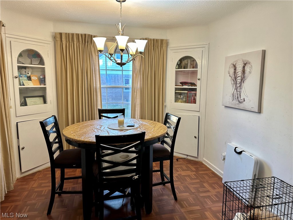 4197 Lambert Road Cleveland, OH 44121 - Photo 2 of 13 Dining area with a chandelier, dark parquet floors, and a textured ceiling
