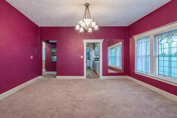 a view of empty room with chandelier and windows