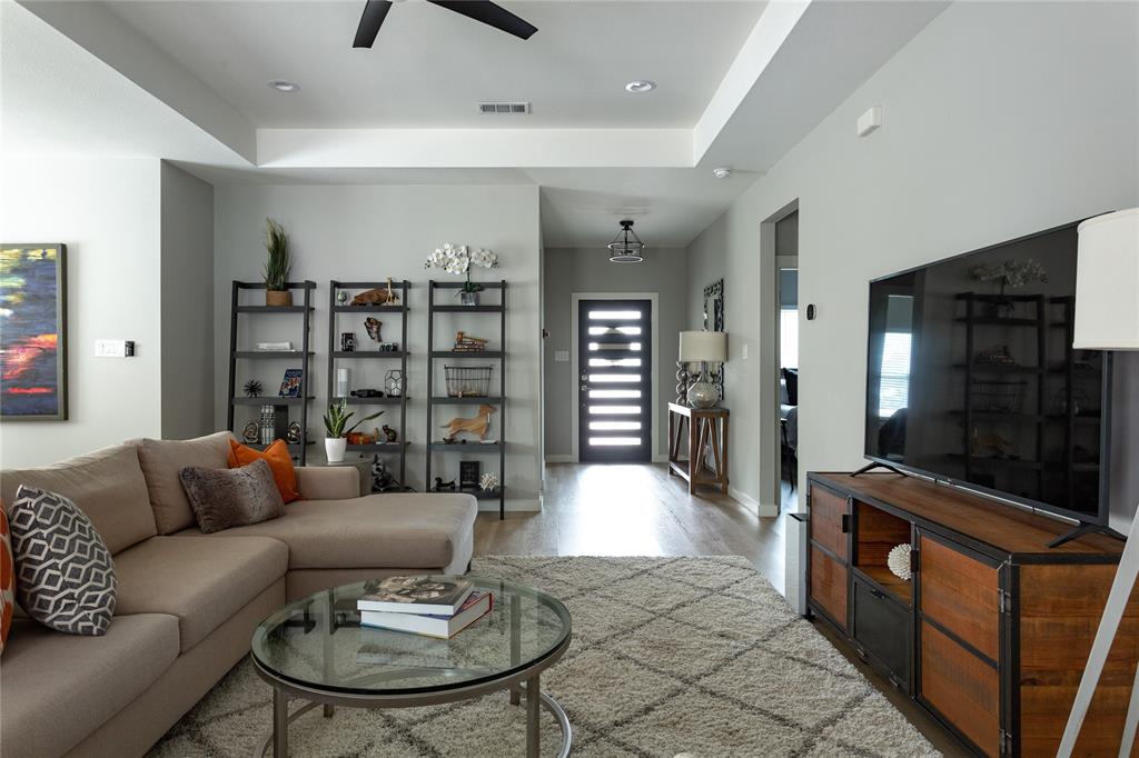 1108 Claude Street Dallas, TX 75203 - Photo 6 of 17 Open-concept living area featuring a tray ceiling with recessed lighting, wood-finish flooring, and a contemporary front entry door with horizontal lites