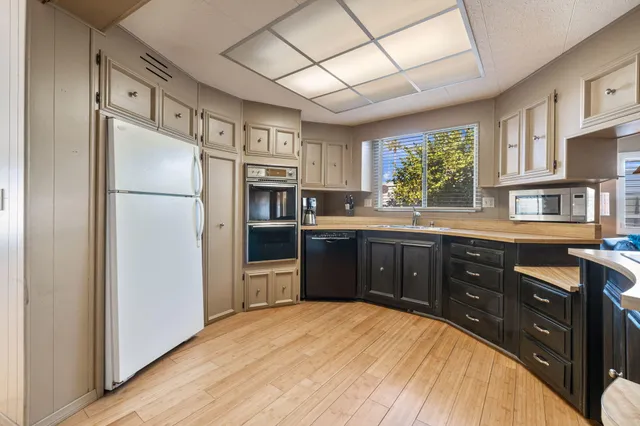 a kitchen with stainless steel appliances granite countertop a refrigerator a sink dishwasher a stove with wooden cabinets