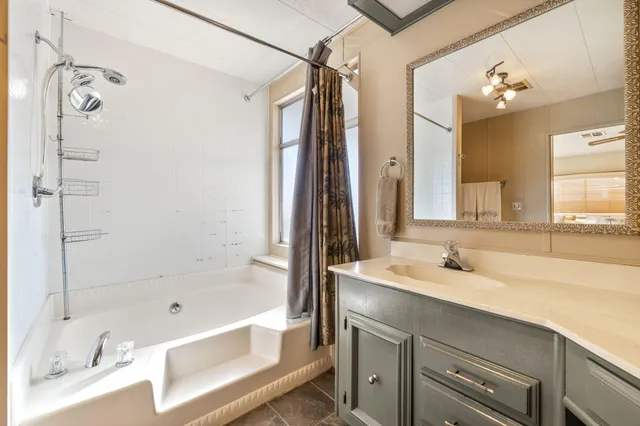 a bathroom with a tub sink and mirror