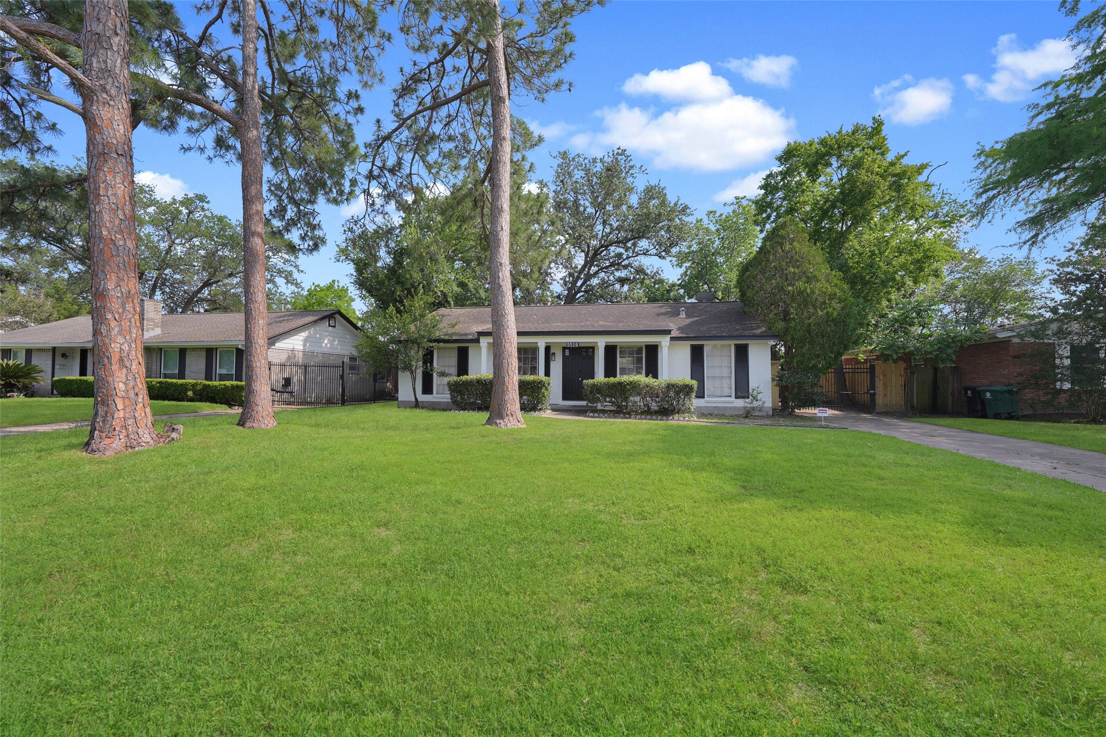Charming single-story home with a spacious front yard featuring mature trees. The house has a classic design with a welcoming porch and a long driveway, offering ample space for parking and outdoor activities.