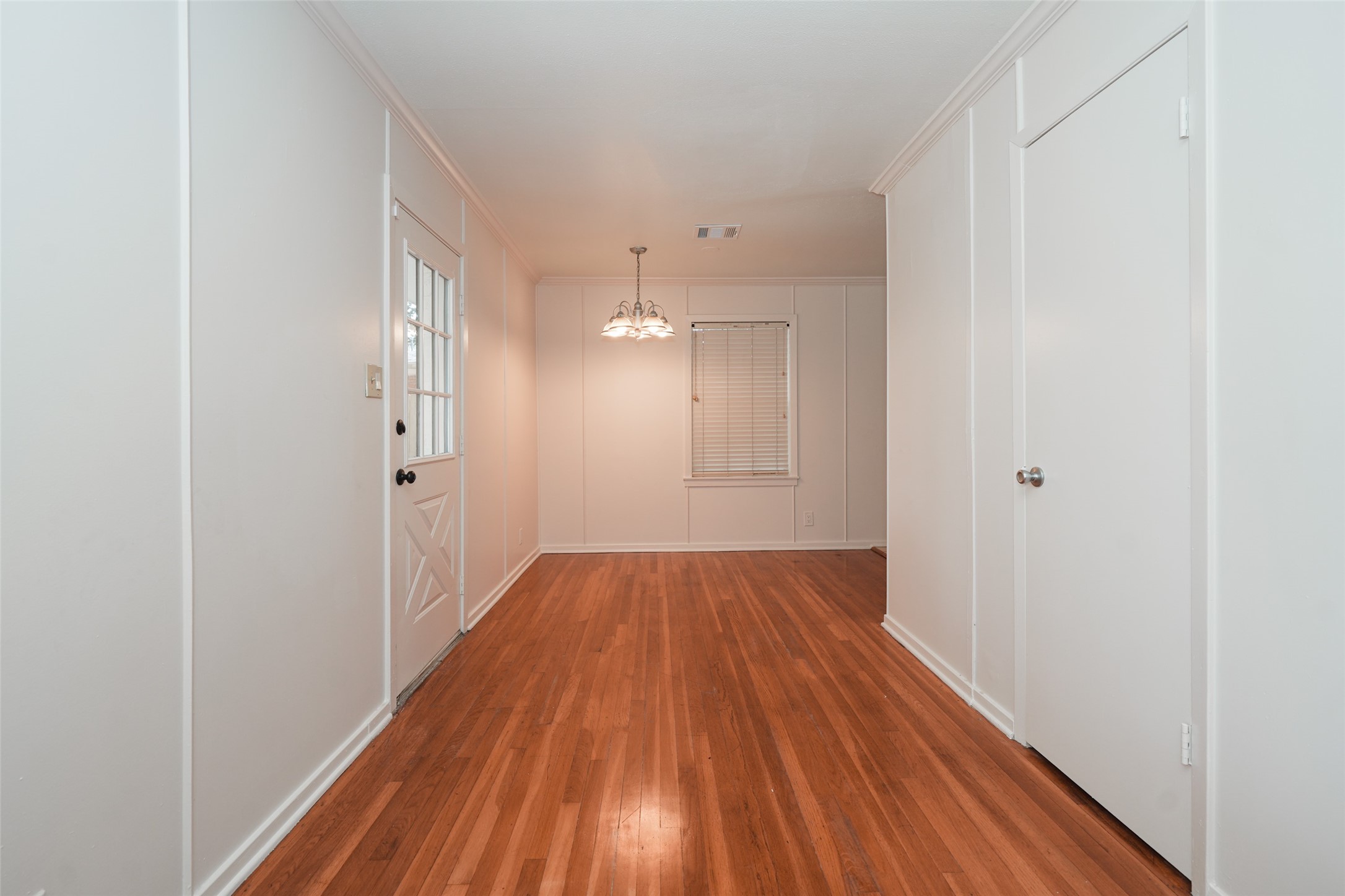 9519 Val Verde Street Houston, TX 77063 - Photo 17 of 27 This room features warm hardwood flooring, white walls, and a central light fixture. It includes a window with blinds, a door, and a closet, offering a cozy, versatile space.