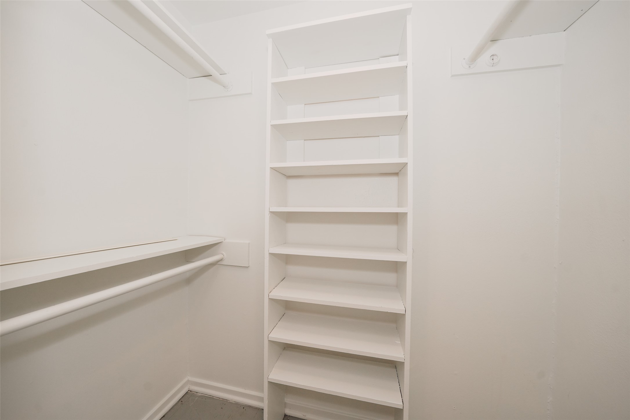9519 Val Verde Street Houston, TX 77063 - Photo 19 of 27 This photo shows a spacious walk-in closet with white shelves and hanging rods, offering ample storage and organization options.