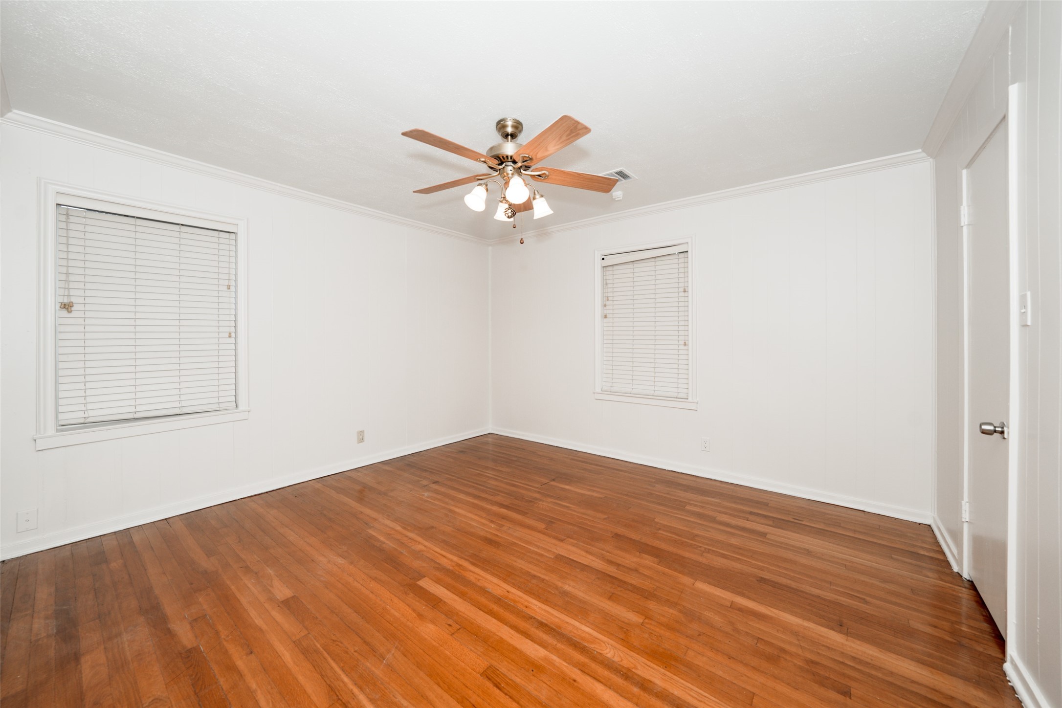 9519 Val Verde Street Houston, TX 77063 - Photo 20 of 27 This room features hardwood flooring, white walls, and two windows with blinds. It has a ceiling fan with lights, creating a bright and airy feel.
