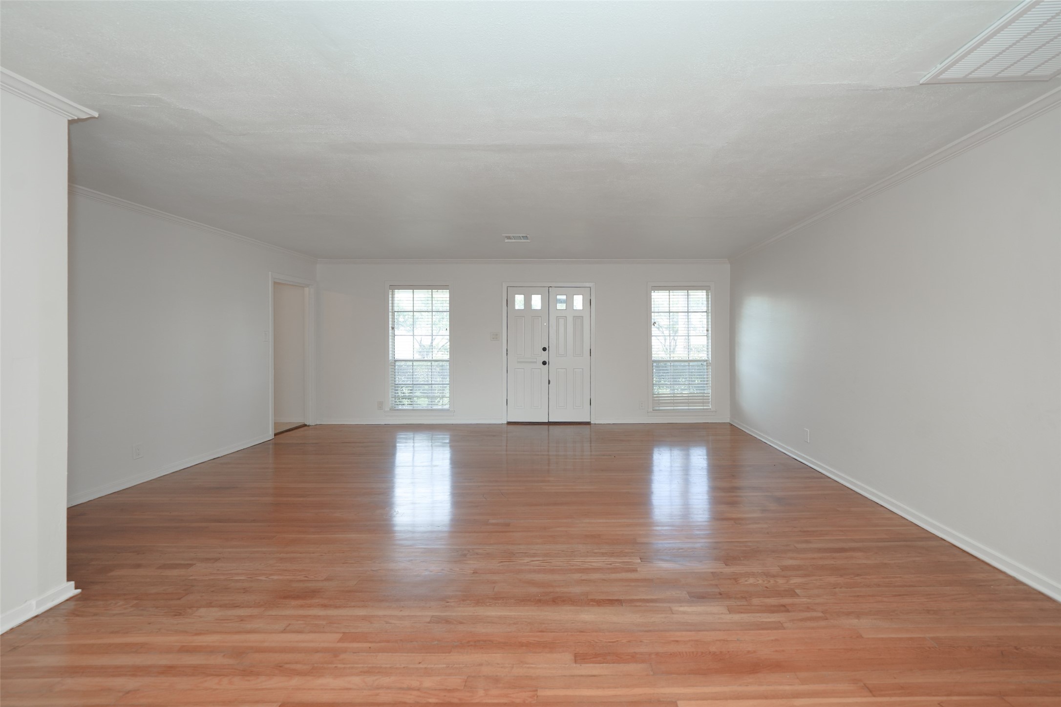 9519 Val Verde Street Houston, TX 77063 - Photo 9 of 27 This spacious living room features polished hardwood floors, two large windows for natural light, and a central front door, creating a bright and welcoming entryway.
