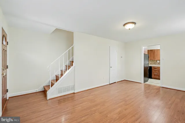 a view of an empty room with wooden floor and stairs
