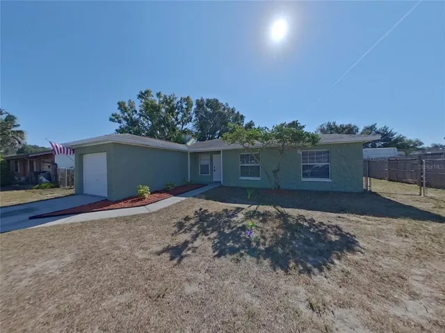 a view of a house with a yard and a large tree