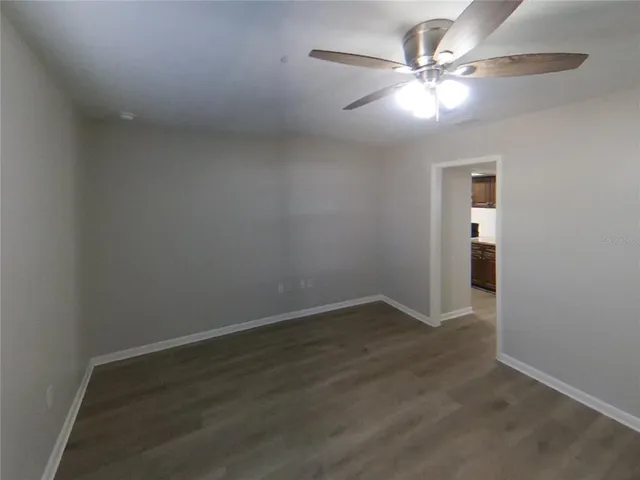 an empty room with wooden floor and fan