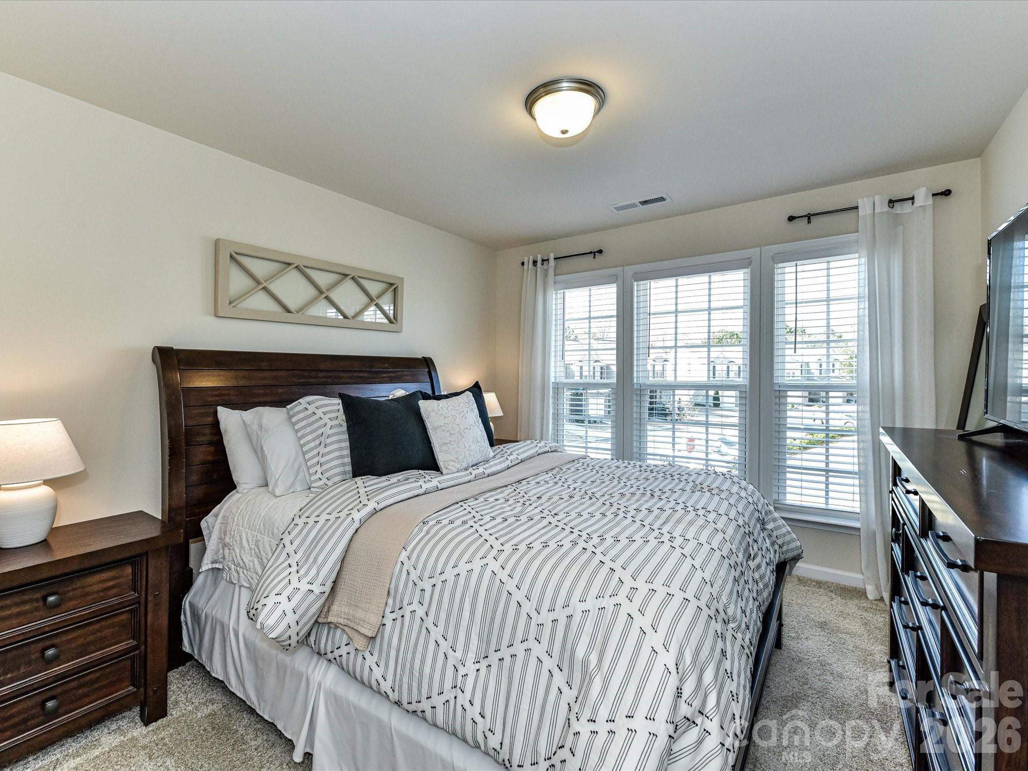 806 Canoe Song Road Fort Mill, SC 29708 - Photo 24 of 39 a bedroom with a bed and a flat tv screen on dresser next to a window