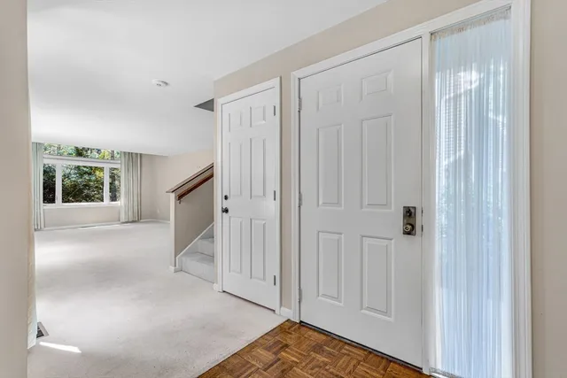 a view of an empty room with window and chandelier