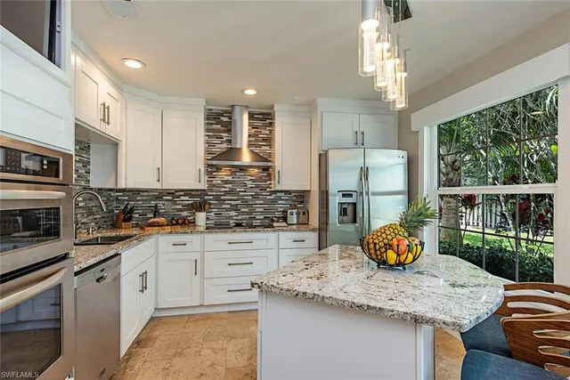 a kitchen with stainless steel appliances kitchen island granite countertop a table chairs in it and wooden floors