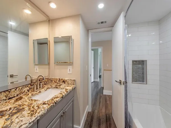 a bathroom with a granite countertop sink mirror and a bathtub