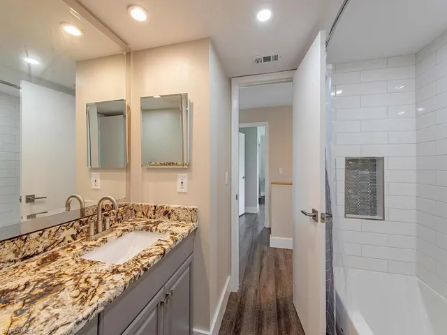 a bathroom with a granite countertop sink mirror and a bathtub