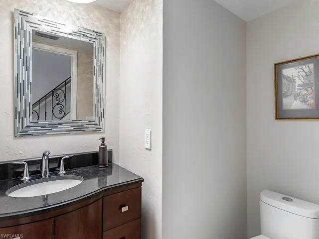 a bathroom with a granite countertop sink vanity mirror and toilet