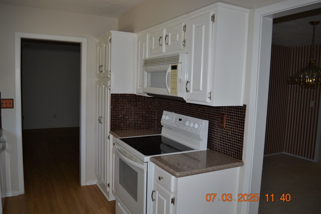 13642 Macon Road Upatoi, GA 31829 - Photo 8 of 34 a kitchen with granite countertop white cabinets and black appliances