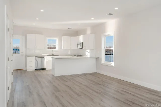 a kitchen with white cabinets and wooden floor