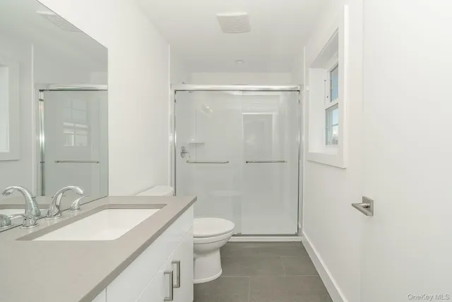 a bathroom with a granite countertop sink a toilet and shower