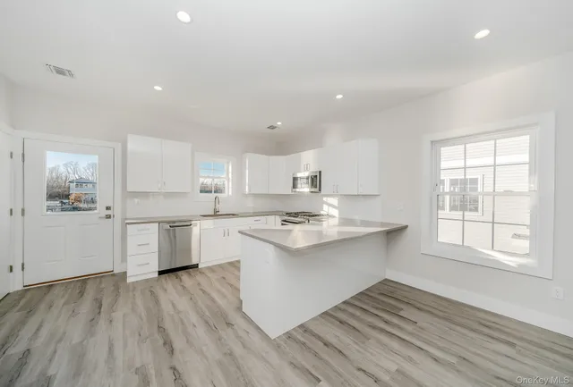 a kitchen with a sink cabinets wooden floor and stainless steel appliances