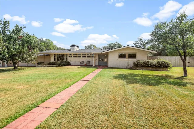 a view of a house with a big yard and large trees