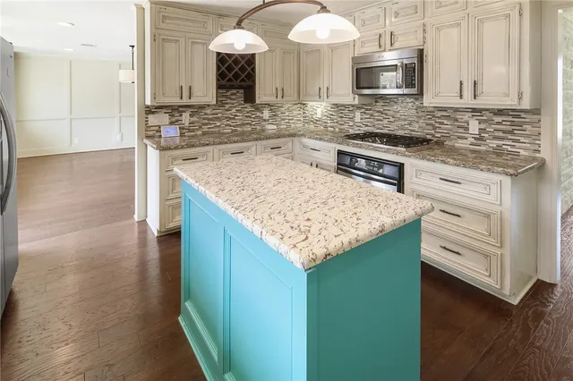 a kitchen with kitchen island granite countertop wooden floors and white cabinets