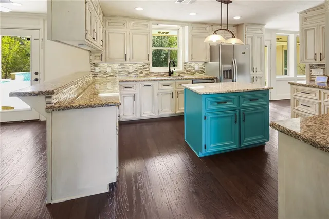 a kitchen with stainless steel appliances granite countertop a sink and a refrigerator