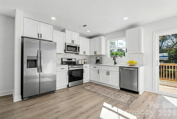 a kitchen with white cabinets stainless steel appliances and a window
