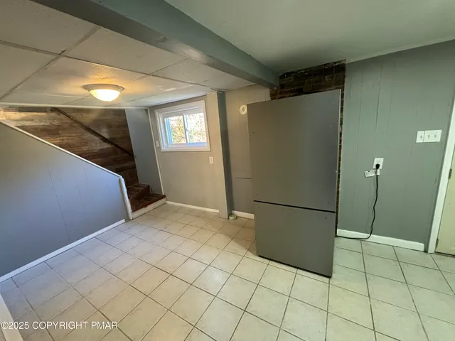 a view of a refrigerator in kitchen and an empty room