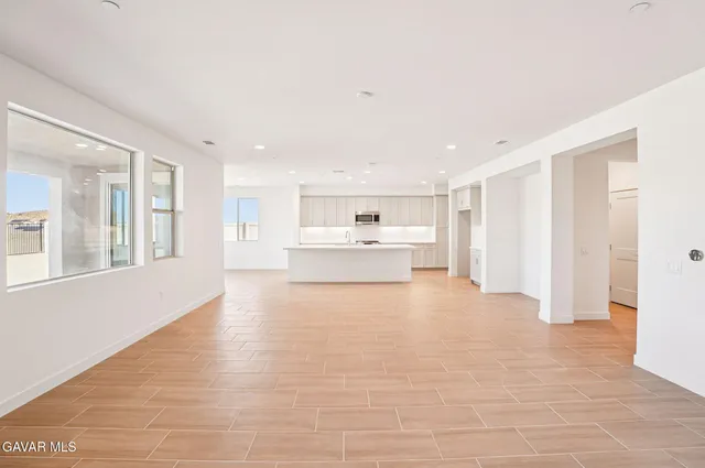 a large white room with kitchen area and refrigerator