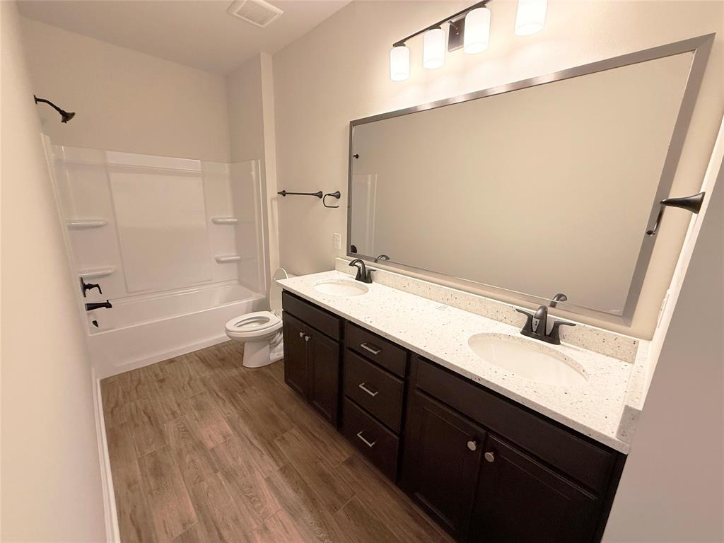 187 Lessie Drive Stonewall, LA 71078 - Photo 21 of 29 a bathroom with a double vanity sink a toilet and a mirror